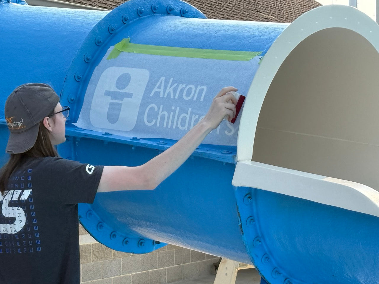DG Creativ Installer applying vinyl graphics to a waterslide at Beachwood Aquatic Center in Beachwood, OH
